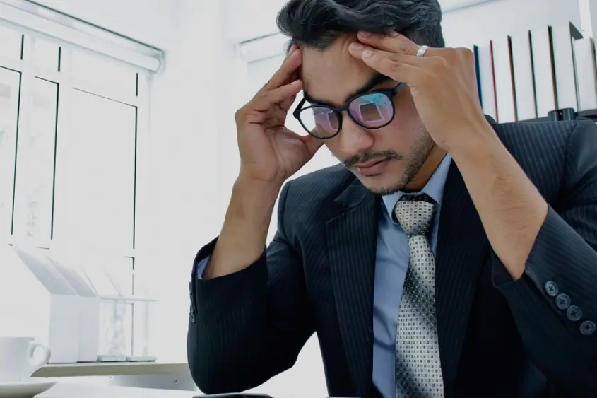 a person in a suit and tie holding his head