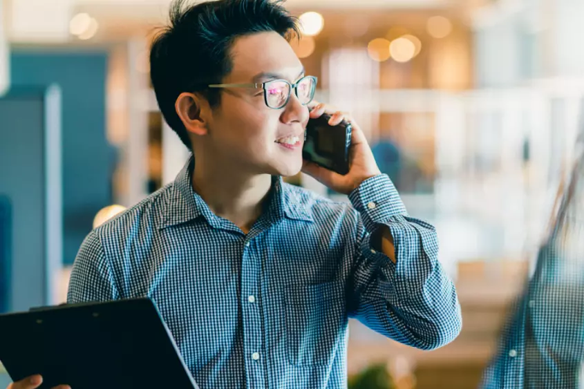 a person holding a laptop and talking on a cell phone